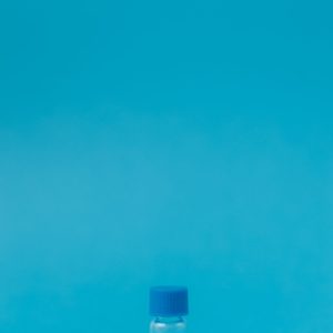 Small glass vial on blue background